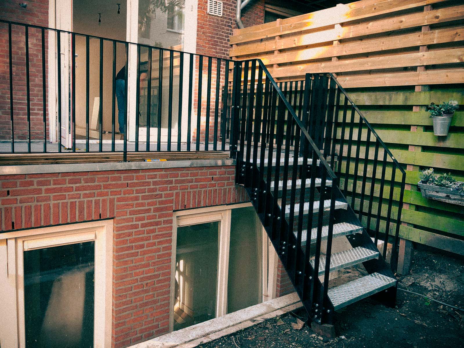 Stalen buitentrap met zwarte spijlenhekwerken van terras naar tuin, Wittenkade Amsterdam